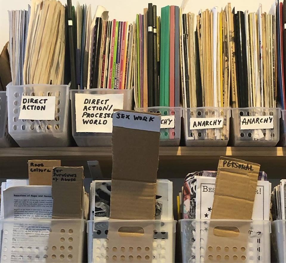 Shelves at the Incendium Radical Library, including works sorted in topics such as Direct Action, Anarchy, and Sex Work.