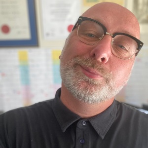 A photo of me: a bald white man, with retro glasses and a short grey beard.